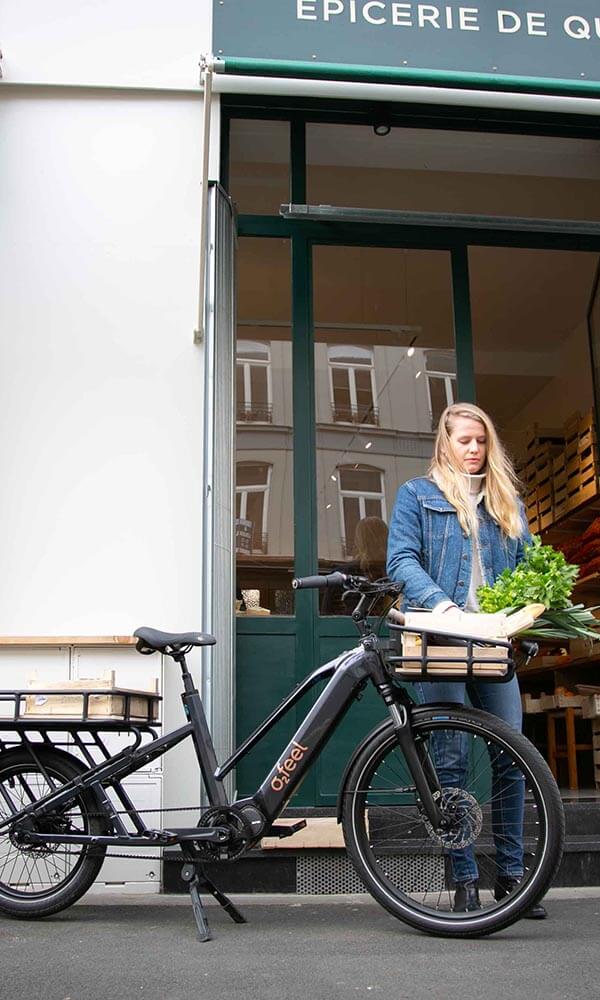 A woman putting her groceries in the front basket of her electric cargo bike