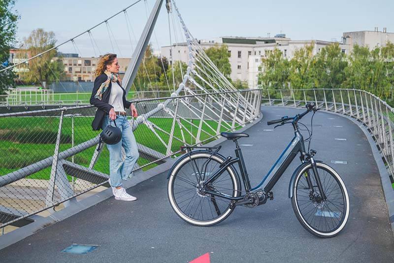 A woman in front of an O2feel e-bike on a bridge